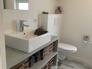 Das Badezimmer mit Waschbecken, Toilette und Regendusch