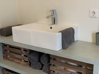 Das Badezimmer mit Waschbecken, Toilette und Regendusch