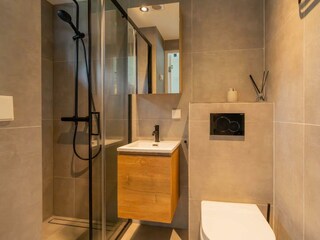 Modernes Badezimmer mit Regendusche, Waschbecken und WC