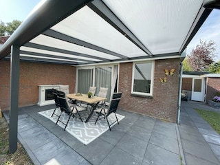 Ein Garten mit Terrasse und Veranda.