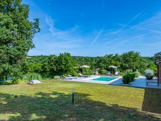 Großer Pool mit Liegestühlen und üppiger Garten.