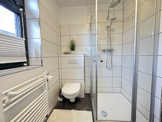 Badezimmer mit Waschmaschine, WC und Dusche