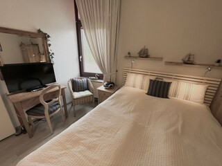 Schlafzimmer mit Doppelbett, extra Fernseher und Rollos