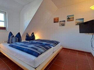 Schlafzimmer mit Doppelbett und TV