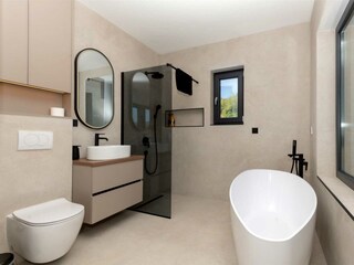 Badezimmer mit Badewanne und Blick auf die Natur