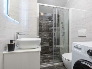 Family bathroom with shower and washing machine.