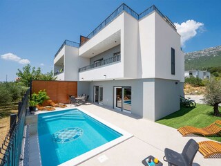 A modern two-story house surrounded by greenery.