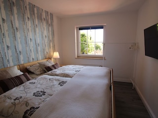 Schlafzimmer mit Doppelbett, Kommode und TV