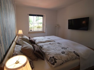 Schlafzimmer mit Doppelbett, Kommode und TV