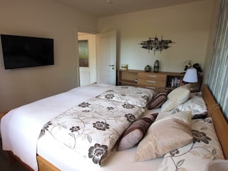 Schlafzimmer mit Doppelbett, Kommode und TV