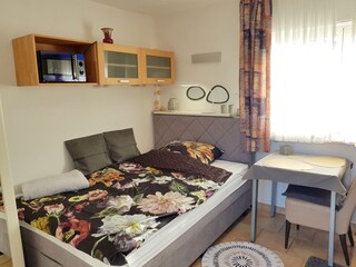 Helles Wohn/Schlafzimmer mit bequemem Boxspringbett