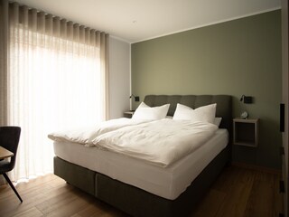 Schlafzimmer mit Bett, Schreibtisch und Kleiderschrank