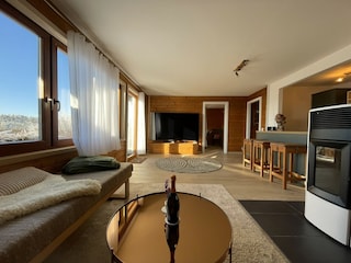 Heller Wohnbereich mit großem TV und warmen Pelletofen