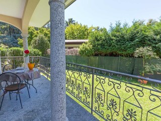 Covered terrace equipped with table and chairs.