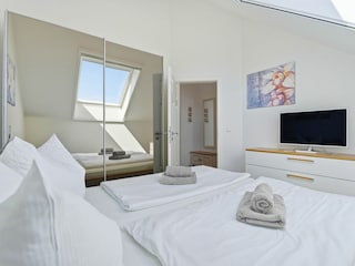 Schlafzimmer mit Doppelbett und TV