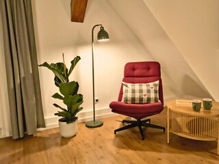 Wohnzimmer mit Lesesessel, Lampe und Beistelltisch