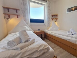 Schlafzimmer mit Einzelbetten und Stauraum unter den Betten