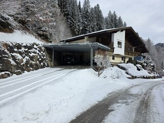 Hauszufahrt im Winter mit Auto-Unterstand