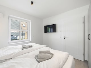 Schlafzimmer mit Doppelbett und TV