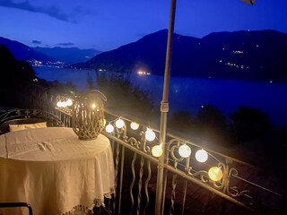 Sonnenbalkon mit magischer Aussicht auf den nächtlich leuchtenden See und die Alpen