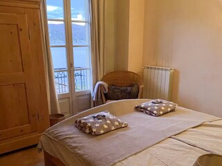 Schlafzimmer mit Doppelbett (1,80 × 2,00 m), traumhaftem See- und Bergblick und Balkonzugang