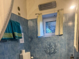 Freundliches Badezimmer mit Dusche, Waschmaschine und -trockner sowie Fenster