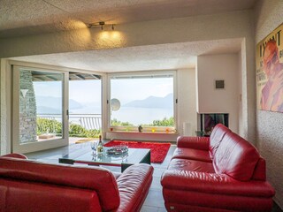 Großzügiger, lichtdurchfluteter Wohn-/ Essbereich mit Panoramafenster, Ledersofas, Kamin, Esstisc...