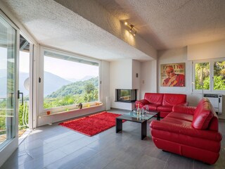 Großzügiger, lichtdurchfluteter Wohn-/ Essbereich mit Panoramafenster, Ledersofas, Kamin, Esstisc...