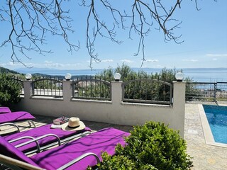 Terrasse am Pool mit Sonnenliegen und Meerblick