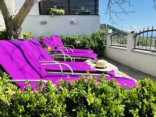 Terrasse am Pool mit Sonnenliegen und Meerblick