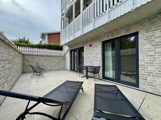 Entspannen Sie auf dieser sonnigen Terrasse mit bequemen Liegen und einem einladenden Tisch.