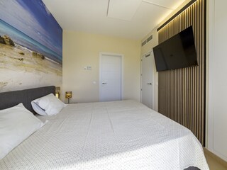 2. Schlafzimmer mit Fernseher und angrenzendem Bad