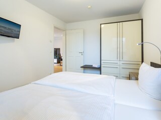Schlafzimmer mit Doppelbett und TV sowie Kleiderschrank