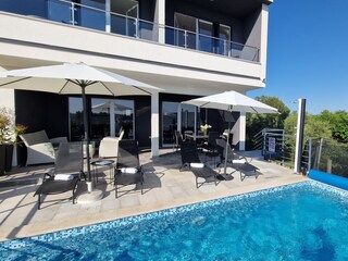 Sun loungers and parasols next to Villa pool