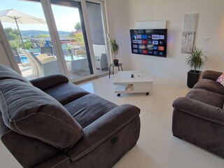 Bequemes Wohnzimmer mit TV und Poolblick in Villa