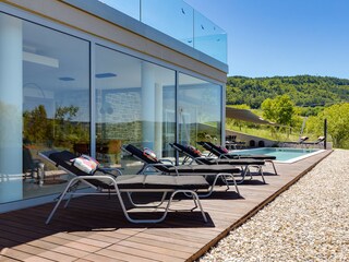 Sun loungers next to pool of villa with mountain view