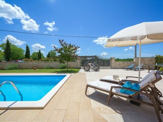 Sonnenliegen zum Entspannen neben Pool einer Villa