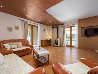 Großes Wohnzimmer mit TV und Poolblick