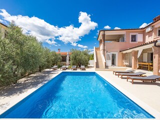 Sonnenliegen und Pflanzen neben privatem Pool