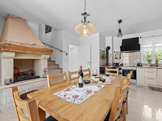 Fireplace, dining table and kitchen in villa