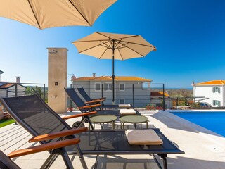 Sonnenliegen und Sonnenschirme neben dem privaten Pool