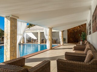 Covered seating area next to the pool in Villa