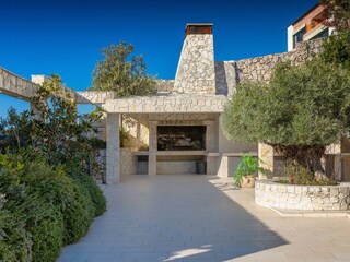BBQ area surrounded by the garden and bushes in Villa
