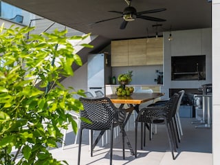 Covered outdoor litchen with dining table in villa