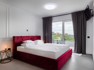 Modern bedroom with balcony, TV and double bed