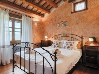 Bright bedroom with wooden ceiling beams, TV an A/C