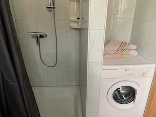 Dusche und Waschmaschine im Badezimmer.