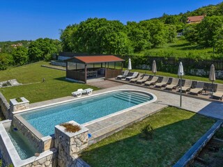 Großer Pool mit Liegestühlen und Garten.