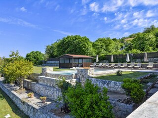 Großer Pool mit Liegestühlen und Garten.