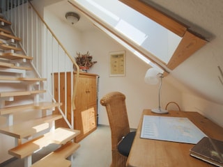 Kleines Zimmer mit Schreibtisch und Raumspartreppe in das Spitzd